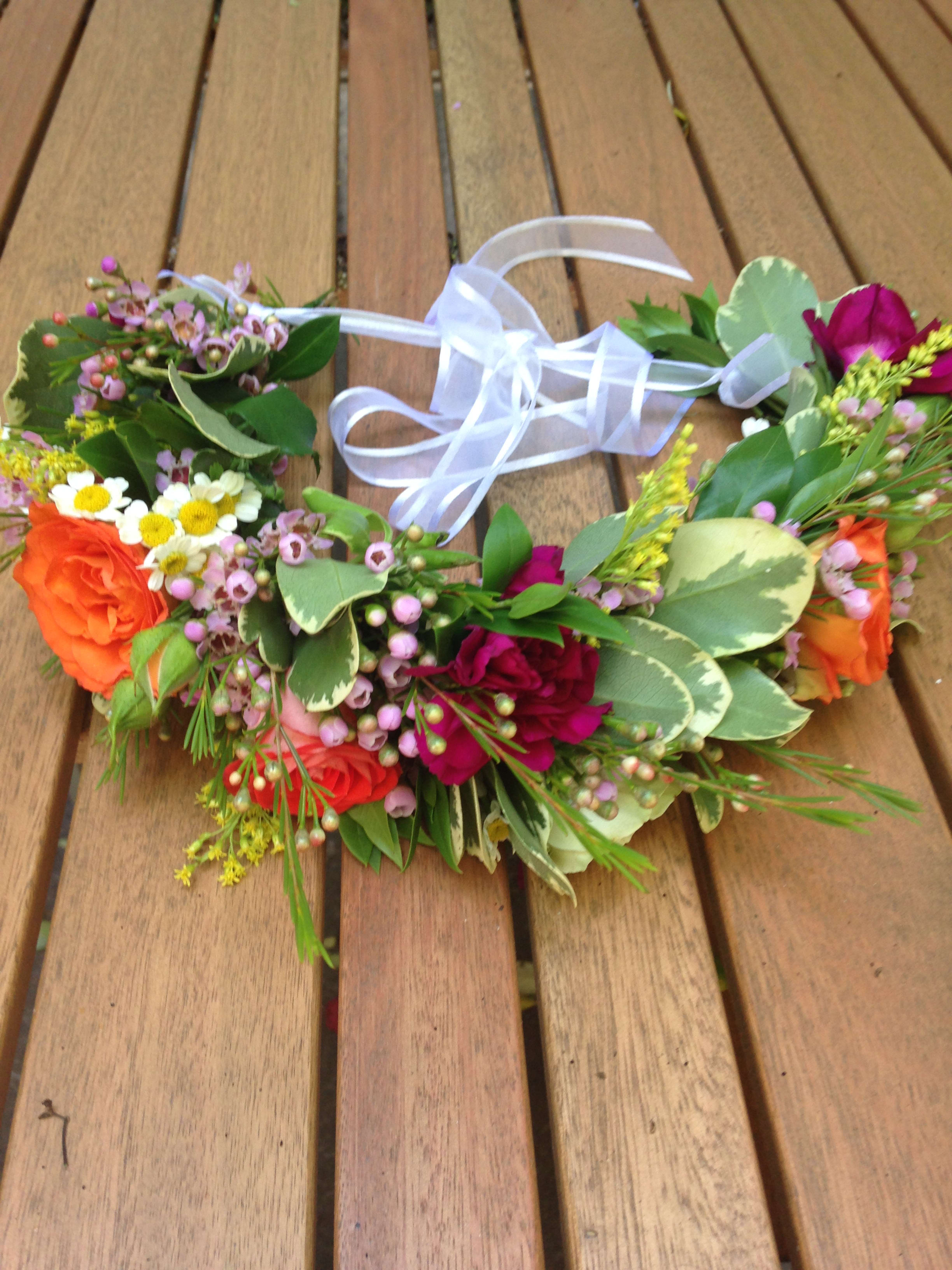 Floral crown with orange and pink roses and a white ribbon tie