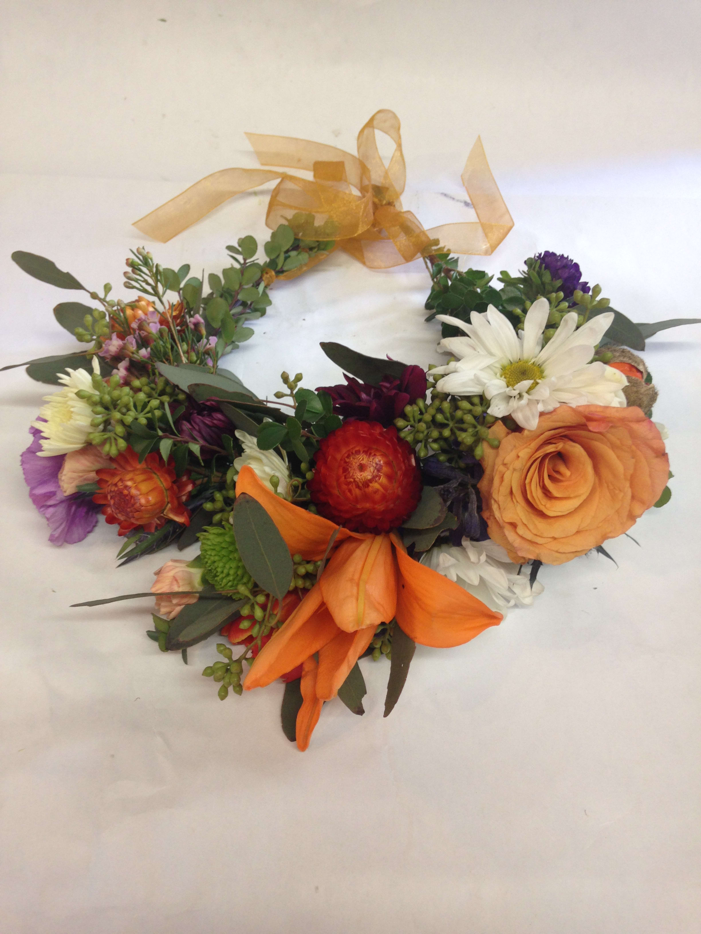 Colorful floral wreath with orange ribbon and mixed blooms