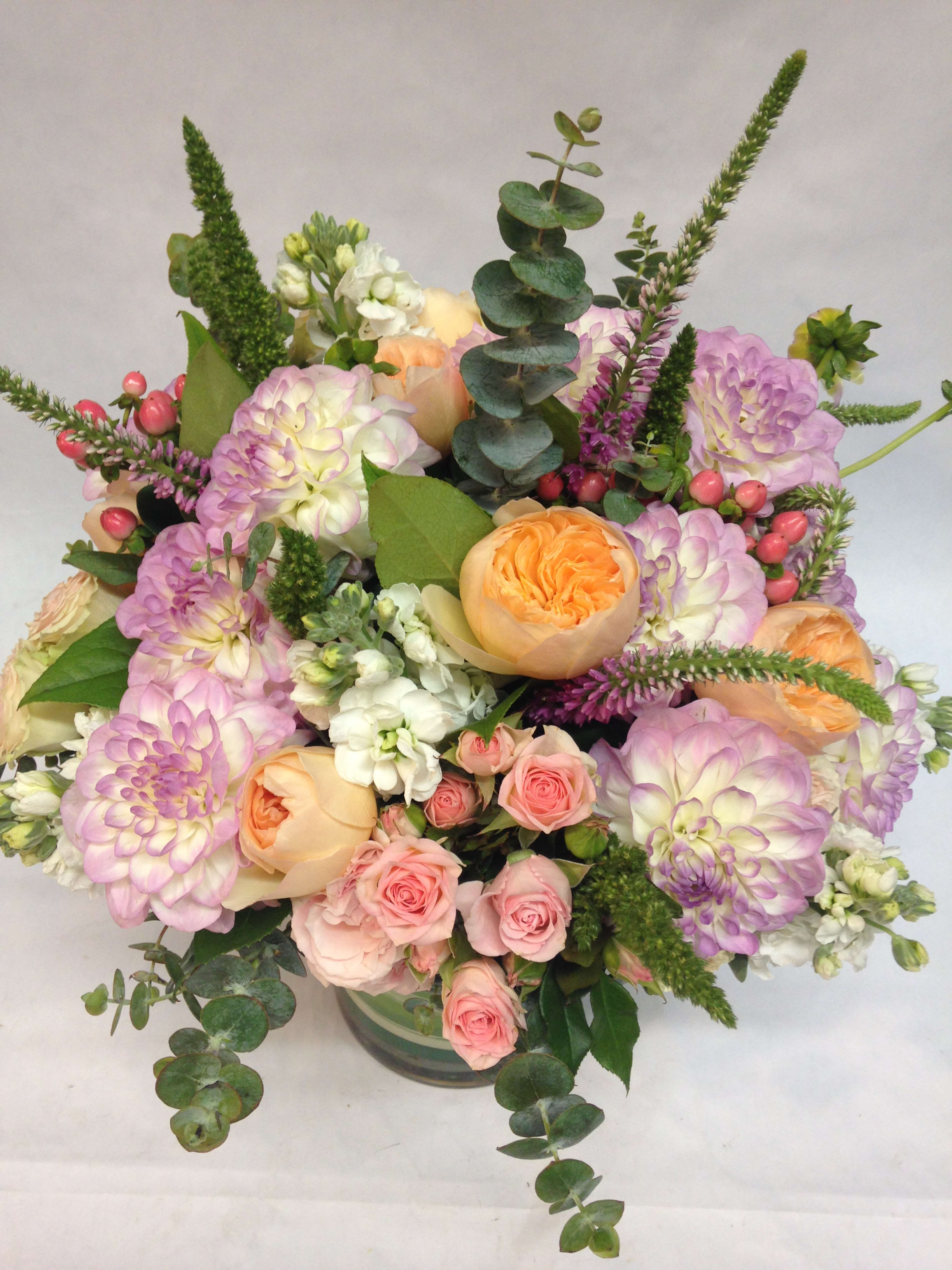 Pastel bouquet of roses, dahlias, and white blooms in a glass vase
