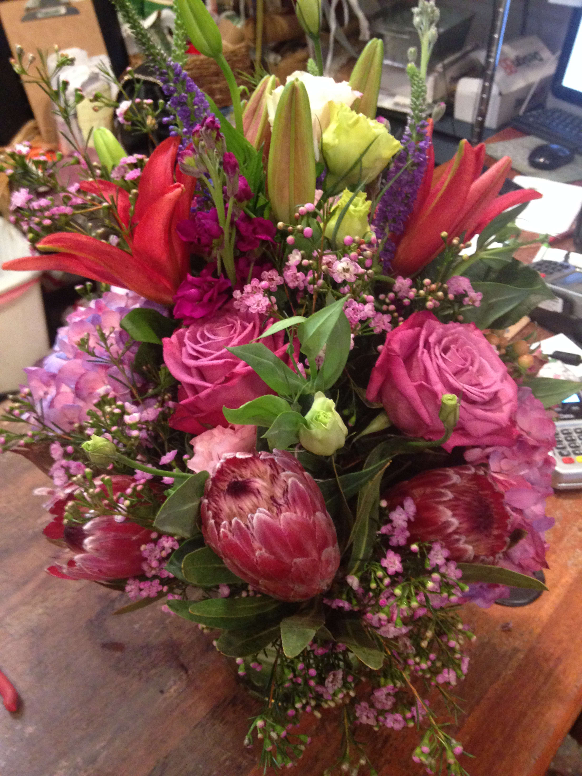 Mixed bouquet with pink roses, red lilies, and purple filler flowers