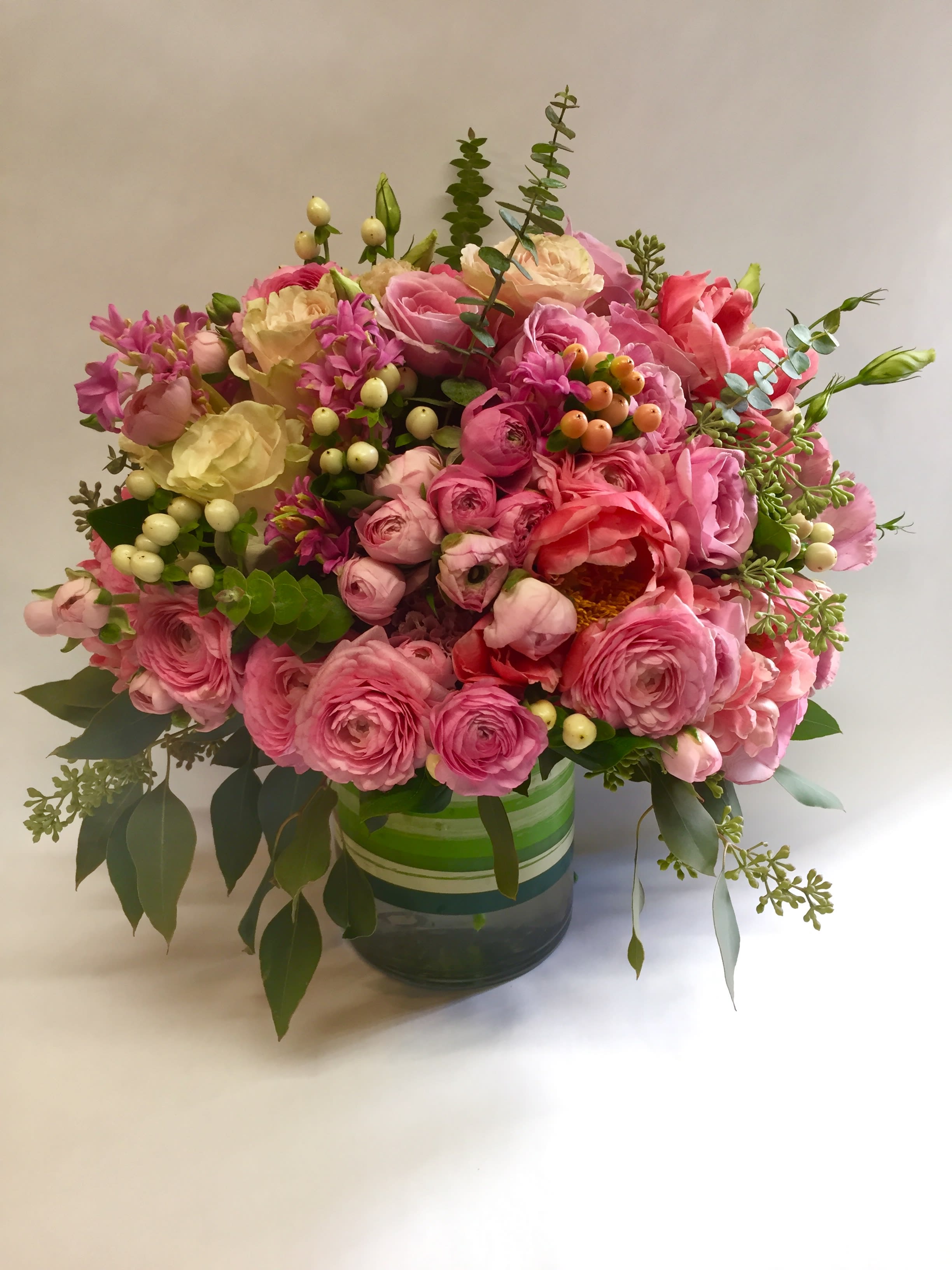 Pink and cream bouquet in a striped glass vase