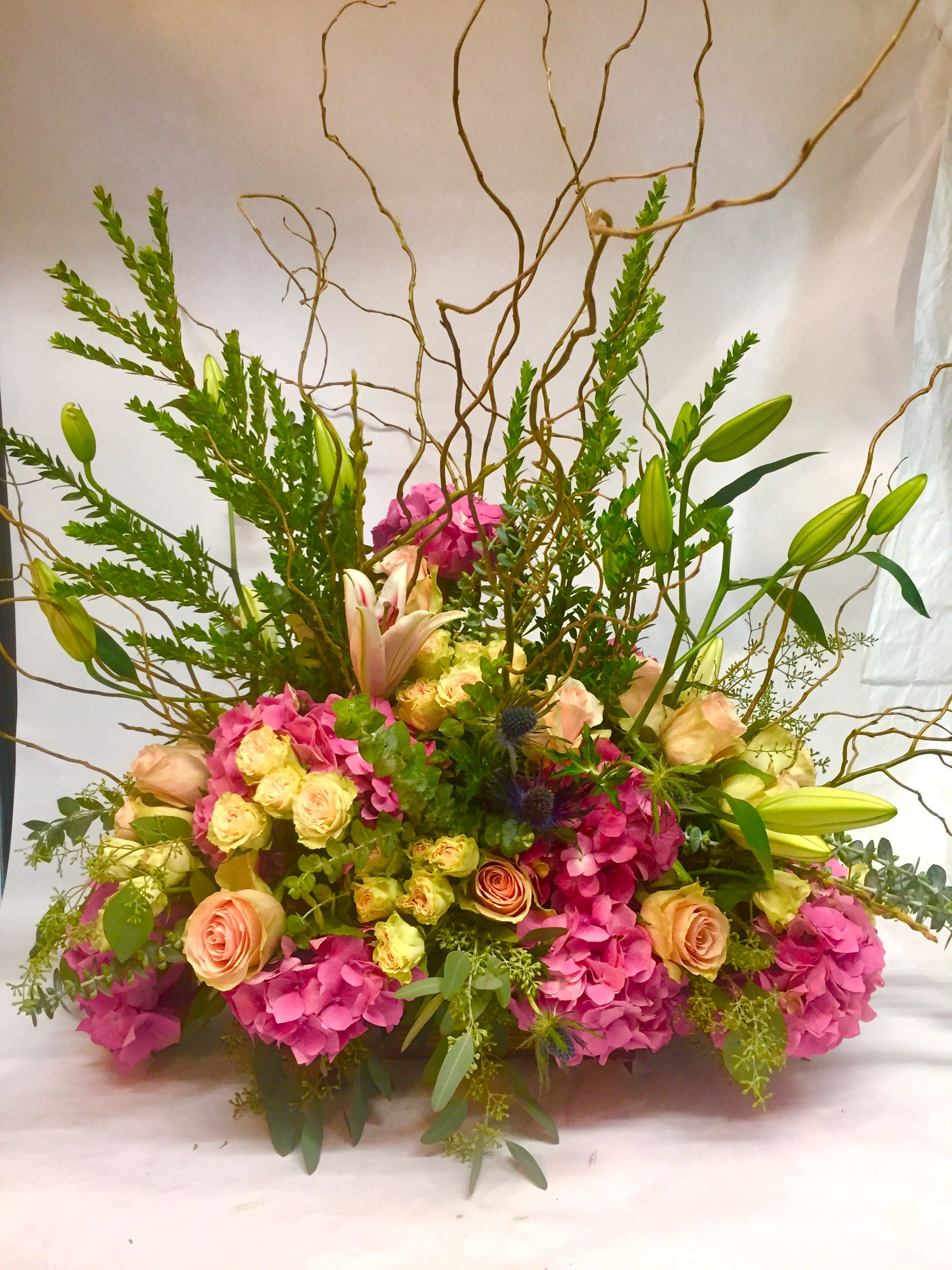 Large bouquet of pink hydrangeas, roses, and lilies with tall branches