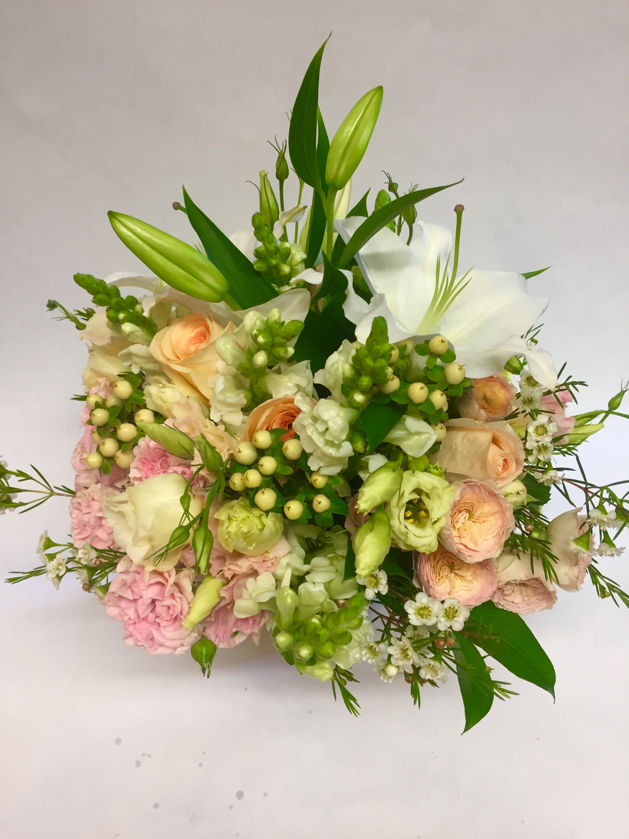 Bouquet of white lilies, peach roses, and pink blooms with green buds