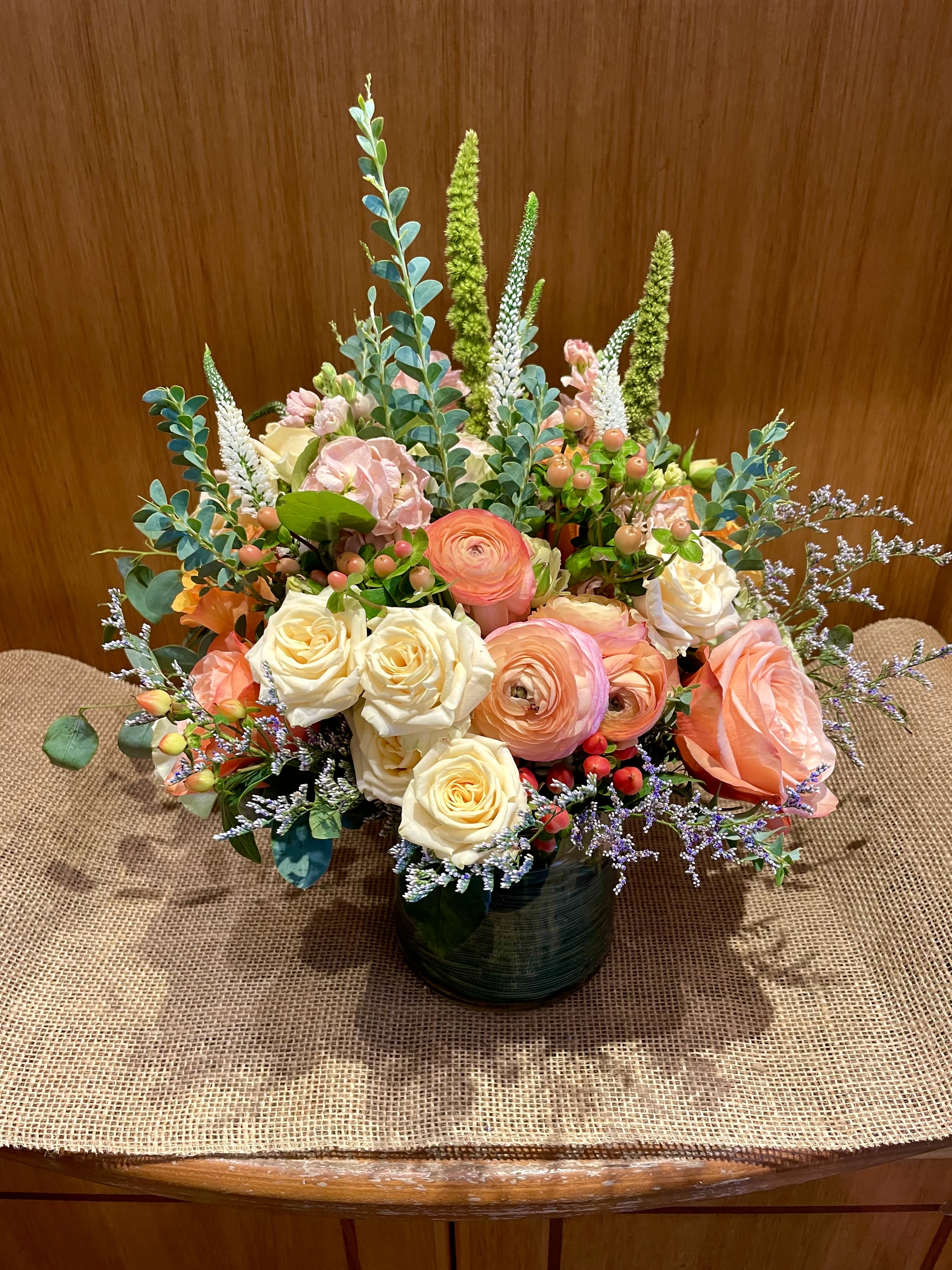 Mixed bouquet of peach and cream roses in a dark vase