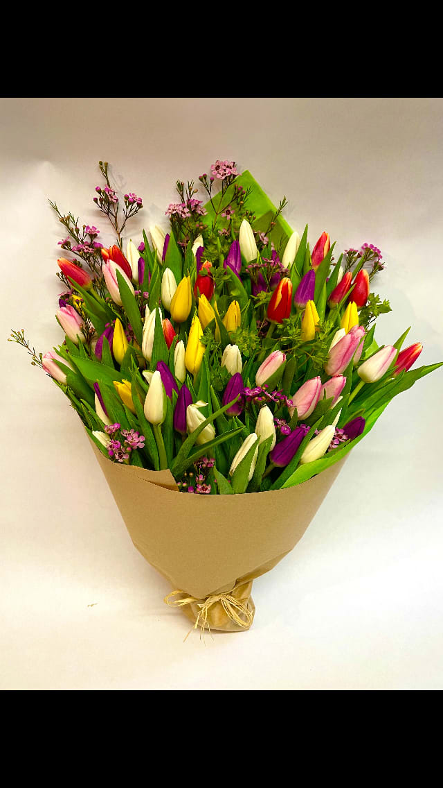 Bouquet of multicolored tulips wrapped in brown paper