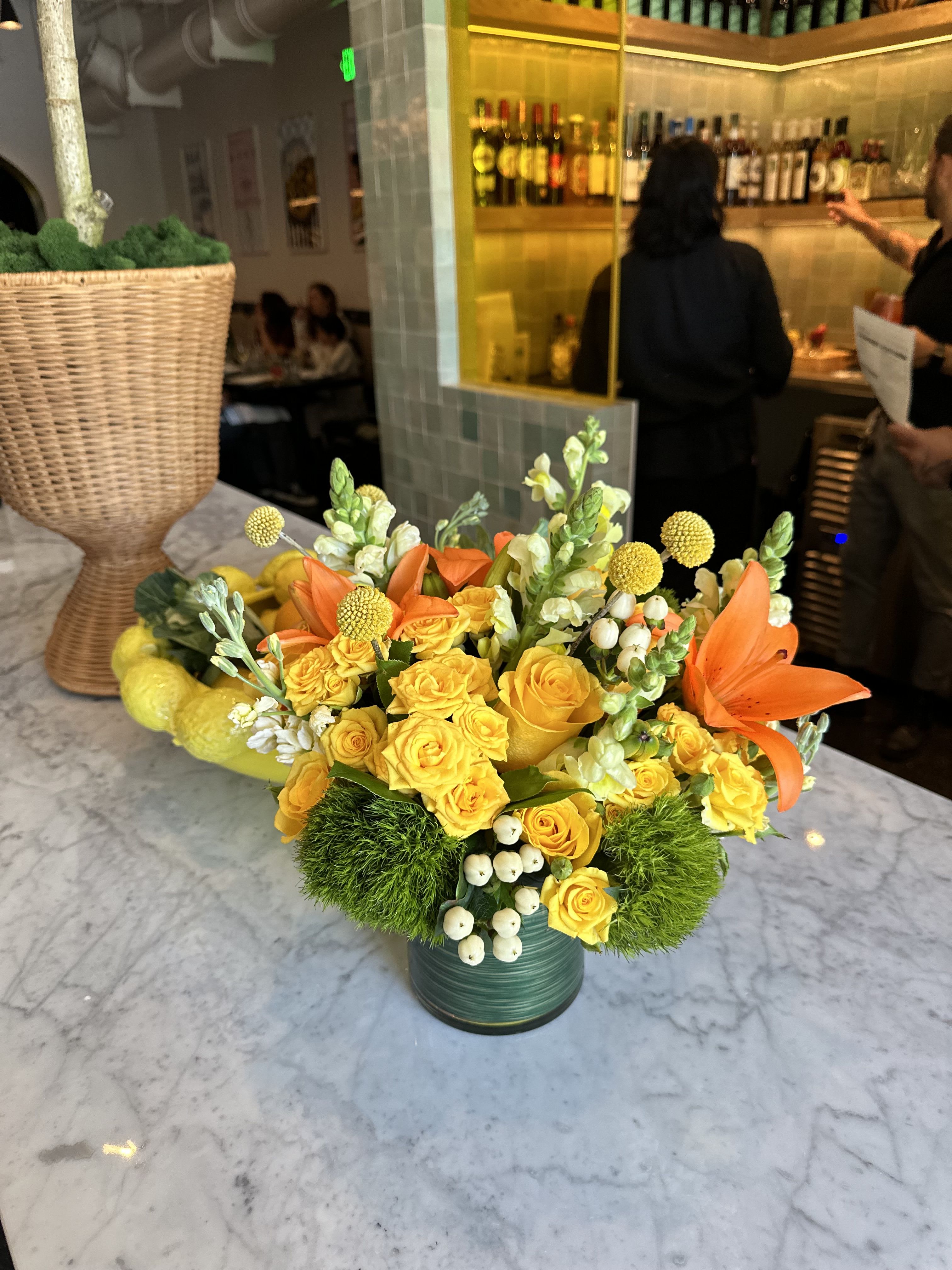Yellow rose arrangement with orange lilies in a green vase