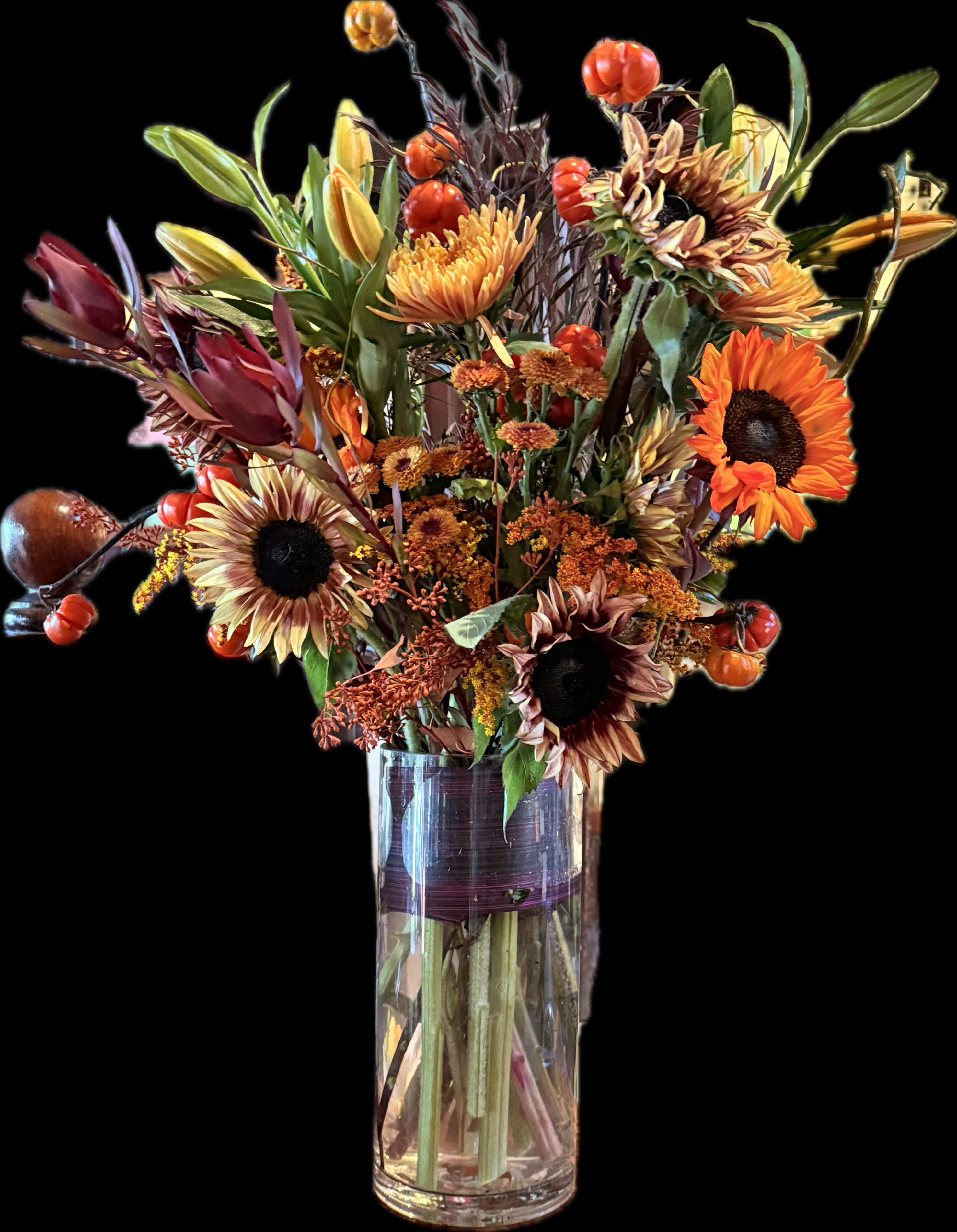 Autumn bouquet with sunflowers and orange blooms in a clear glass vase