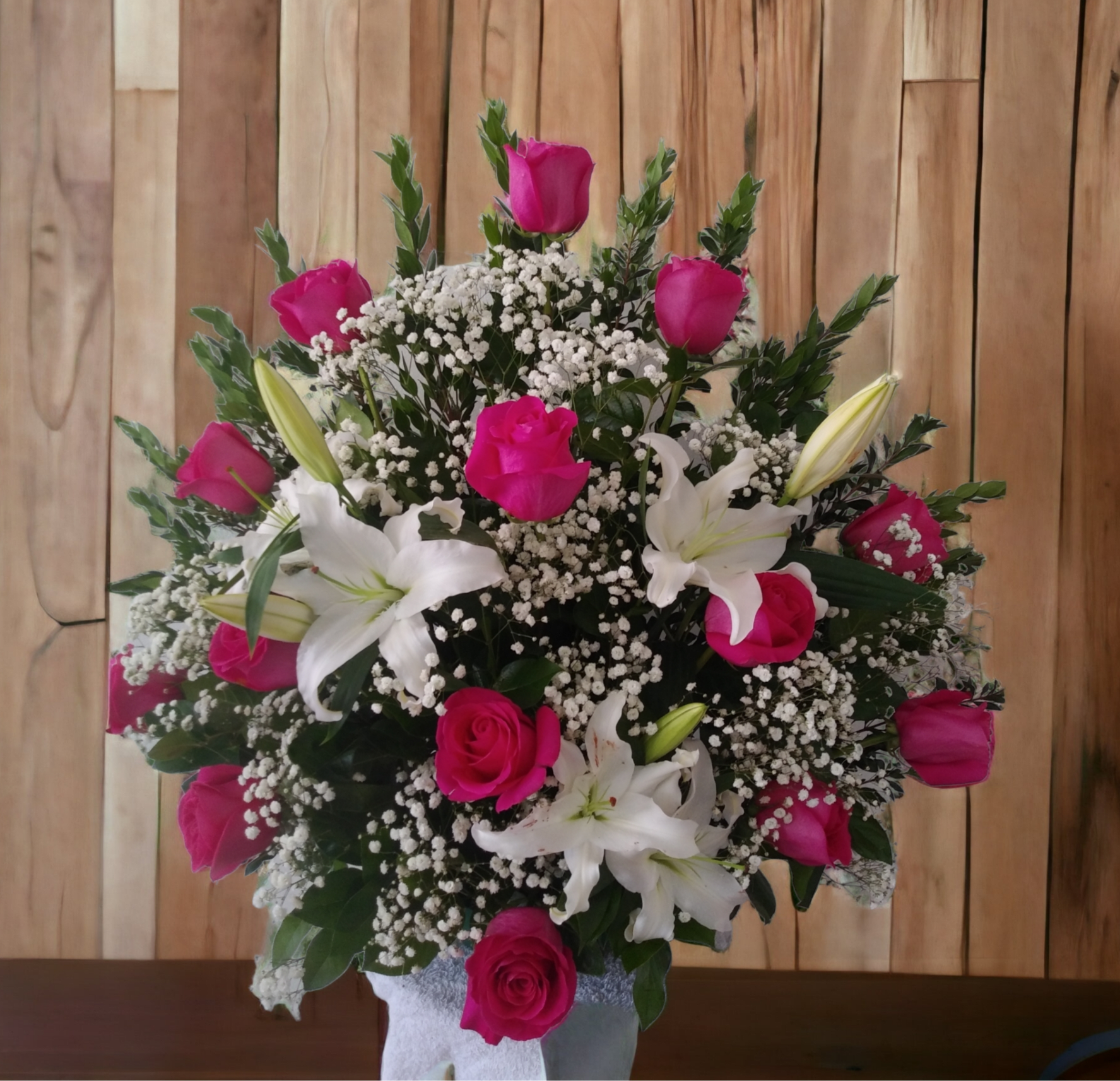 Pink roses and white lilies in a vase with baby's breath