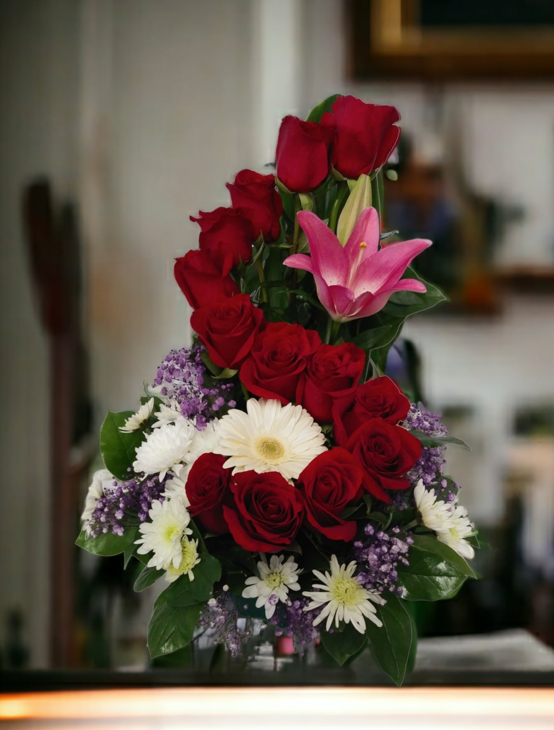 Tall bouquet of red roses, pink lily, and white daisies