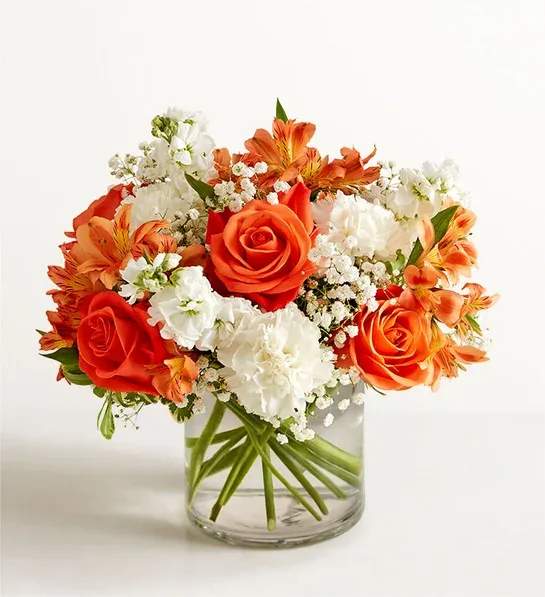 Orange and white flower arrangement in a clear glass vase
