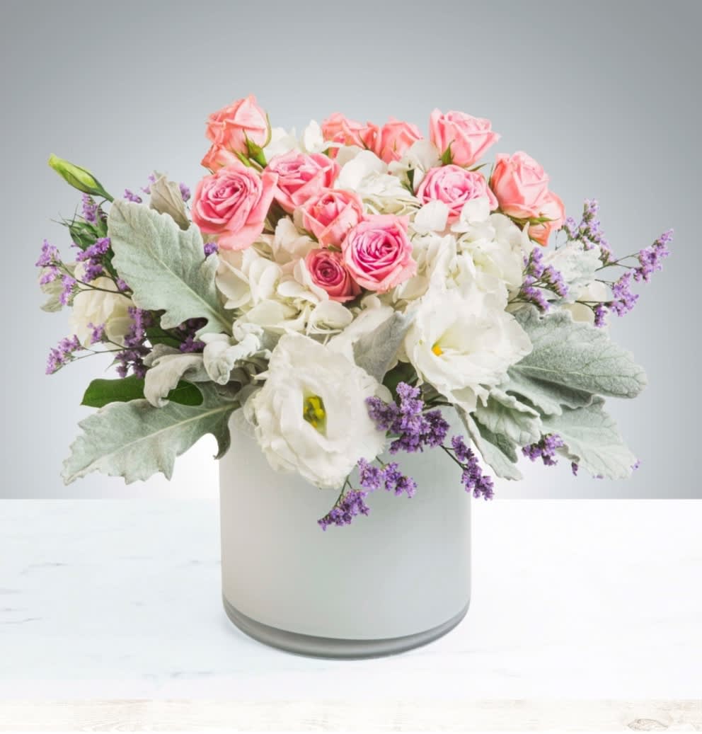 Pink roses and white blooms arranged in a white vase