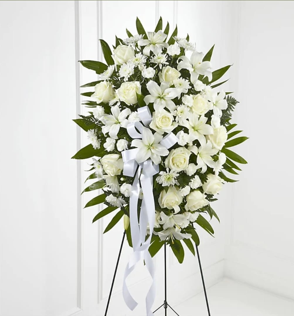 White floral standing spray on an easel with a ribbon bow