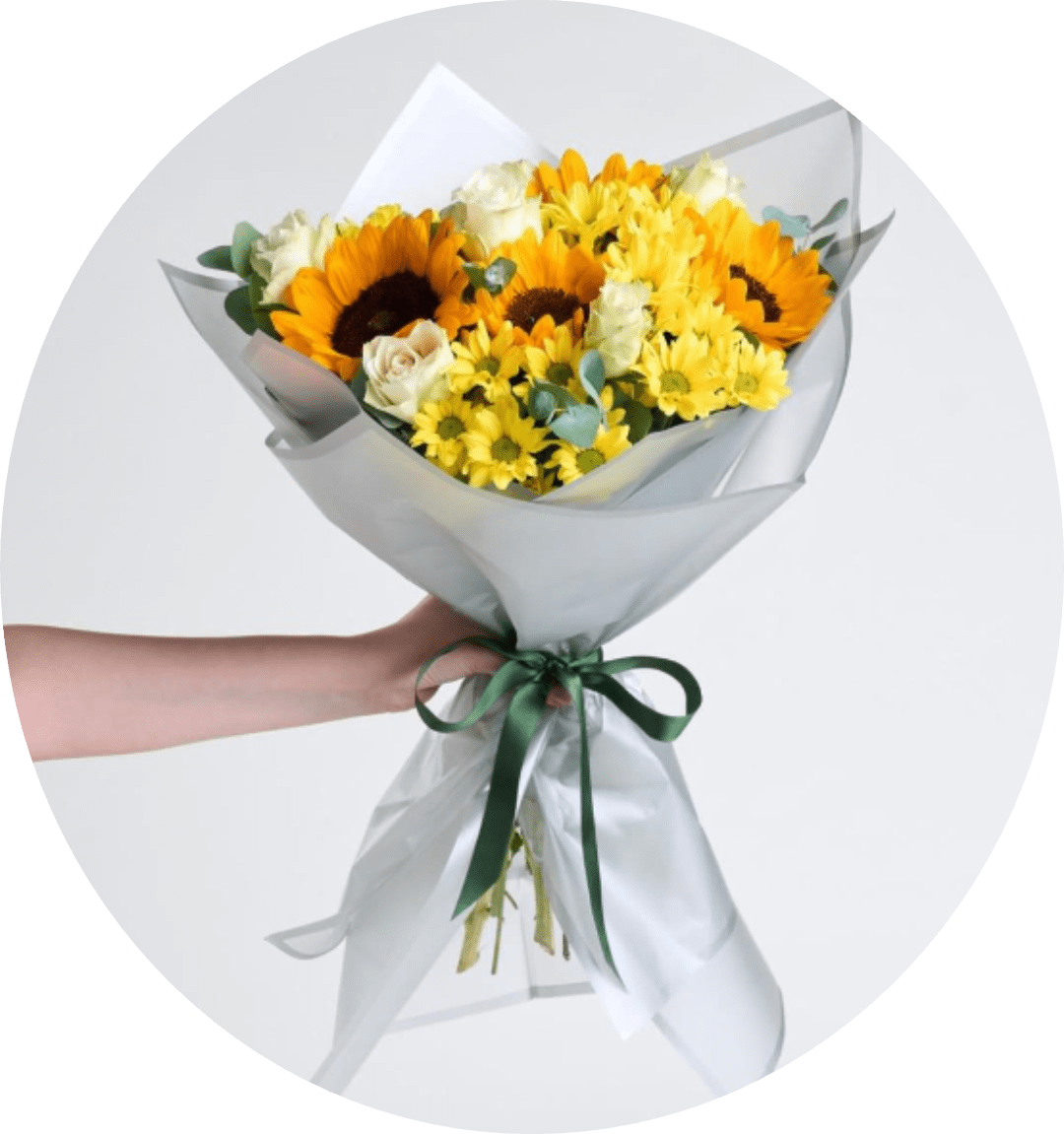DAISY AND SUNFLOWERS - Bright, sunny sunflowers take center stage in this cheerful bouquet-perfect as a birthday bouquet, thank-you gift, or general celebration arrangement that will make the person you're thinking of feel truly seen. Warm yellow chrysanthemums and small yellow daisies surround the focal blooms, while pale and white roses soften the palette with gentle cream tones for an upbeat, friendly impression.  The hand-tied shape reads full and rounded without being formal, wrapped in layered translucent and white paper and finished with a dark green ribbon for a polished, gift-ready presentation. Colors include yellow, white, orange and green; flowers include sunflowers, chrysanthemums, roses and daisies. The bouquet is medium-sized and easy to carry, an instantly uplifting choice that delivers sunny texture, bright color, and timeless charm.  Ideal for cheering someone up, saying thanks, or marking a happy milestone, this arrangement arrives pre-wrapped and ready to present. For best longevity, remove any foliage below the water line and recut stems before placing in fresh water; simple care keeps the bouquet looking bright for several days.
