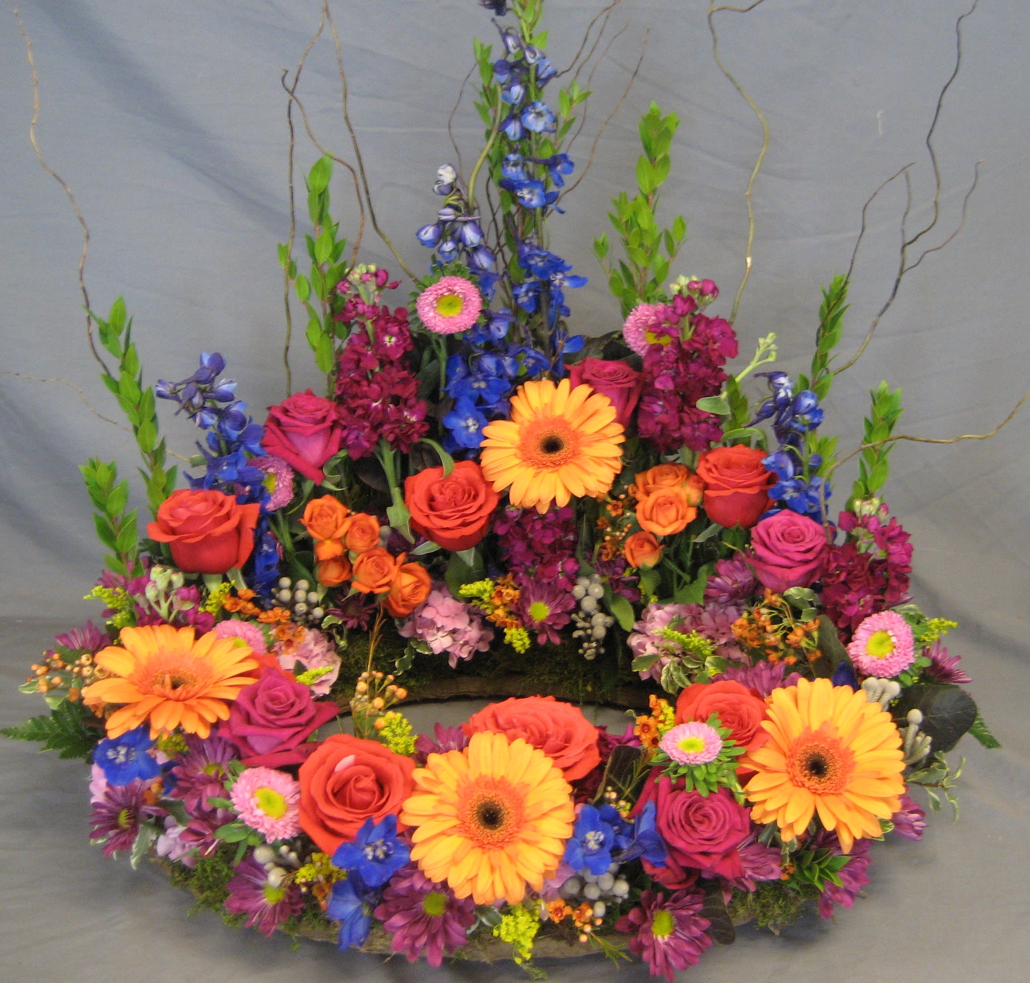 Colorful floral wreath with roses, gerbera daisies, and blue flowers