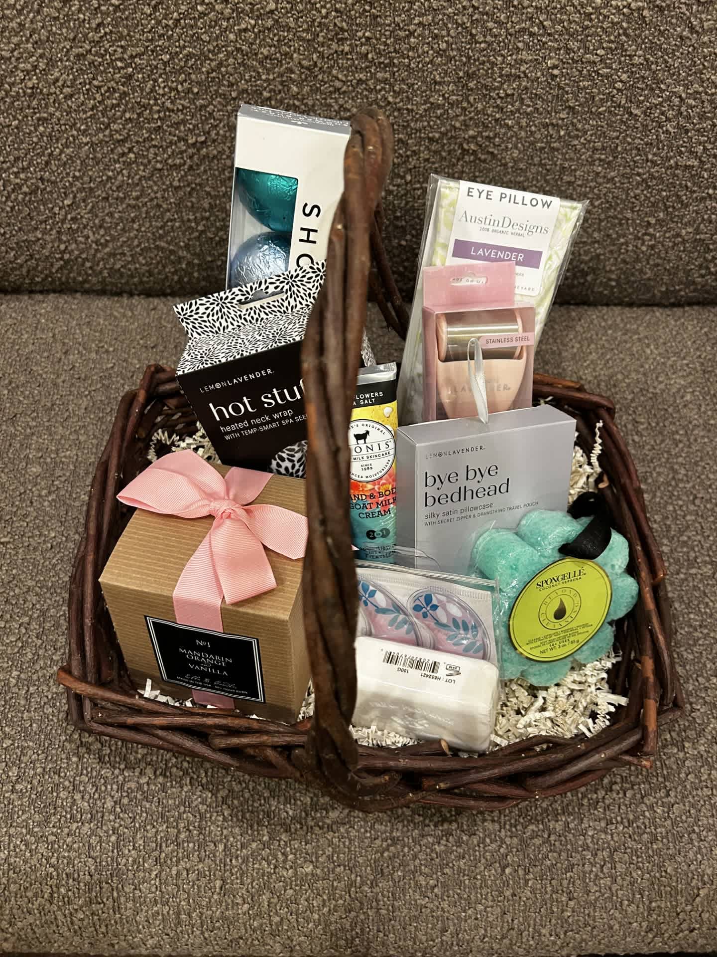 Basket of assorted spa and bath gift items with a pink ribbon