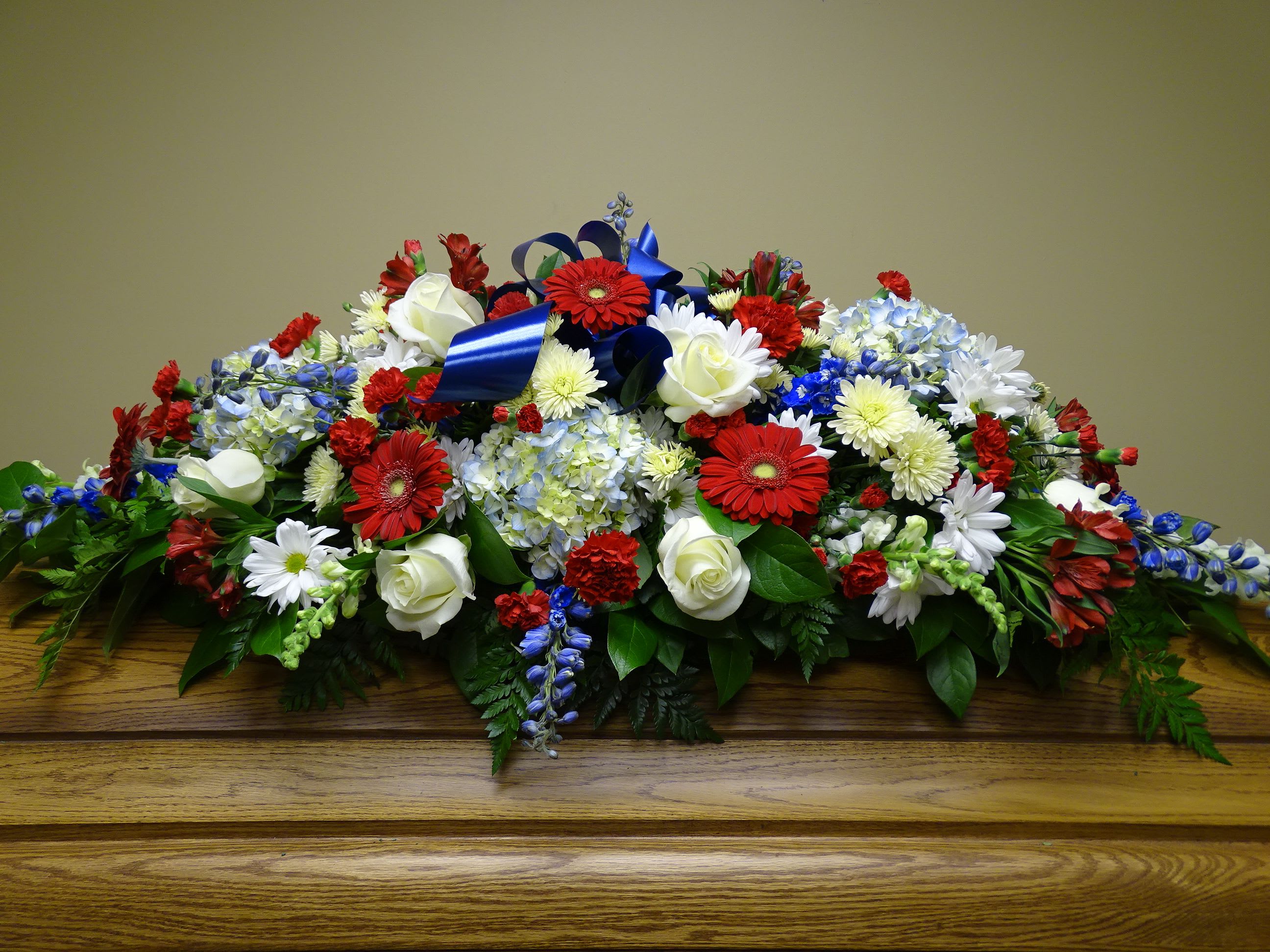 Large floral casket spray with red, white, and blue flowers