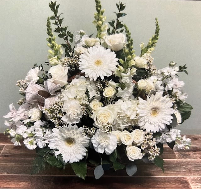 White floral arrangement with daisies and roses in a low container
