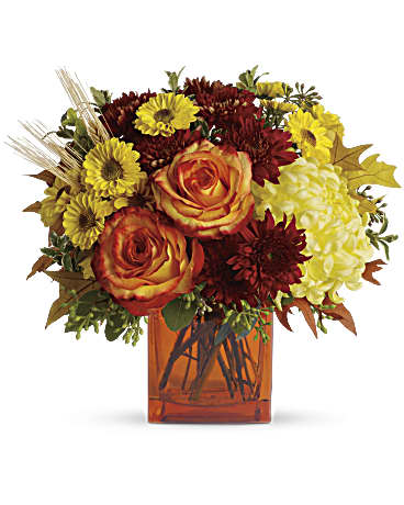 Orange roses and autumn mums in an amber vase