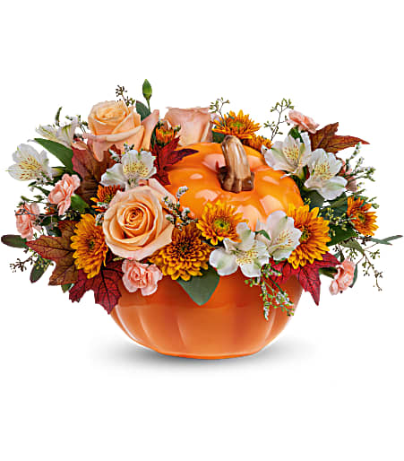 Orange pumpkin-shaped vase with peach roses and autumn flowers