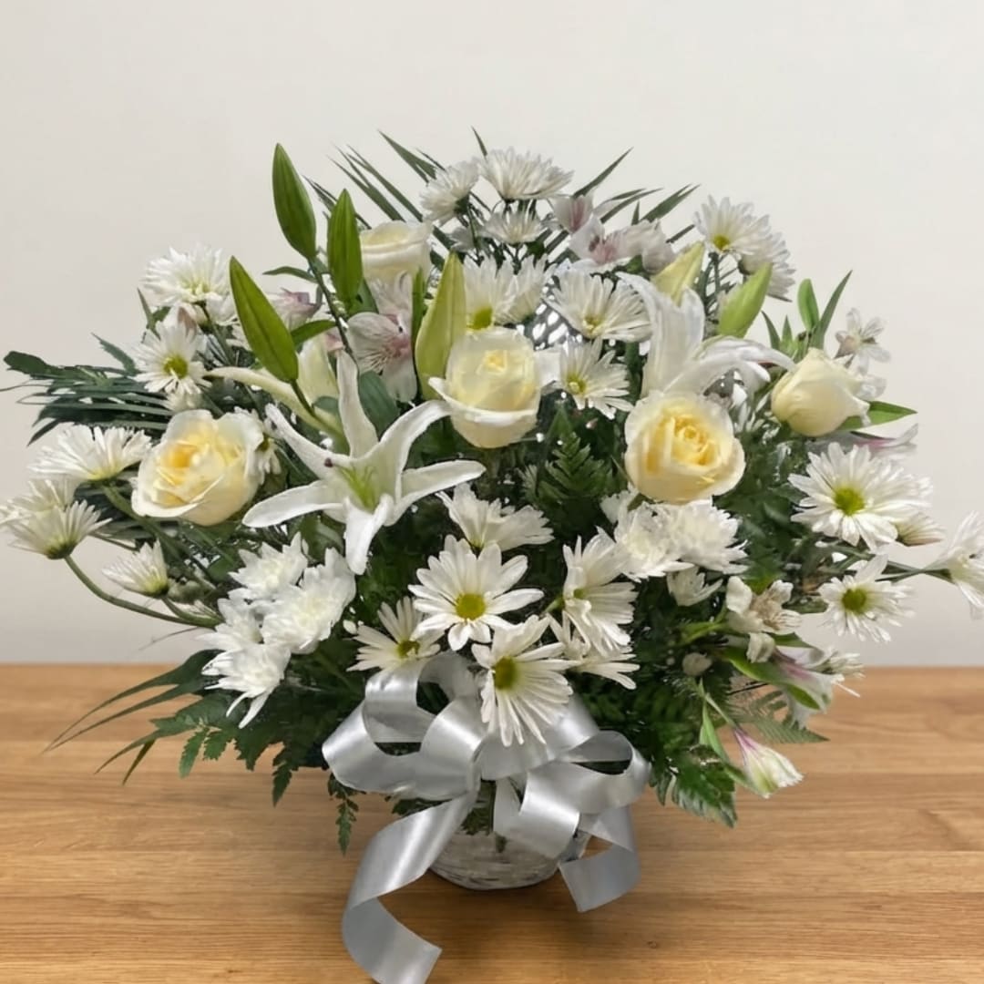 White daisies and cream roses arranged in a basket with a silver ribbon