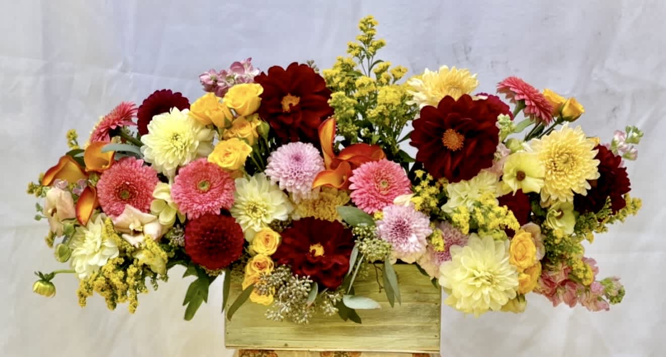 Mixed bouquet of red, pink, and yellow flowers in a wooden box