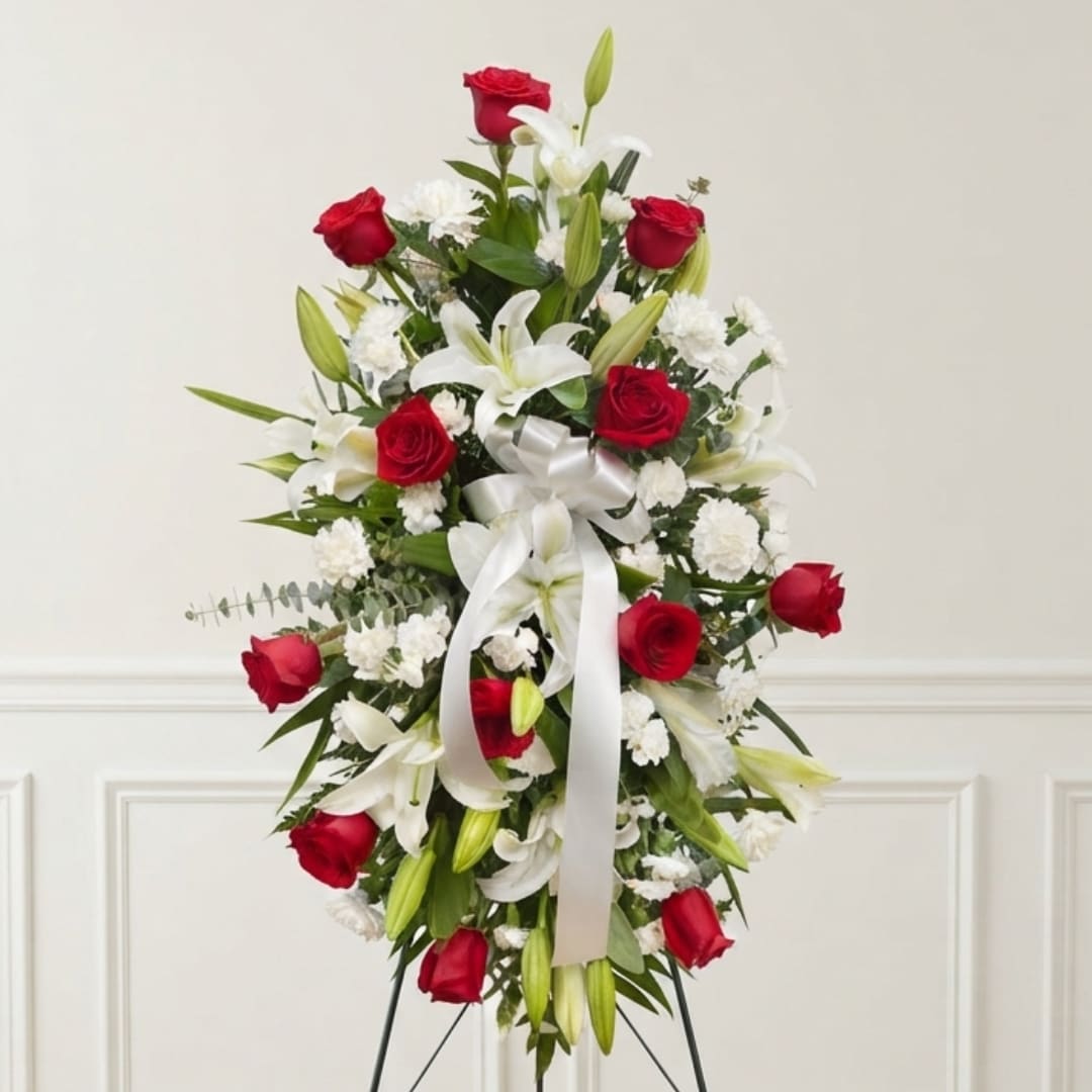 Standing floral spray with red roses, white lilies, and a white ribbon