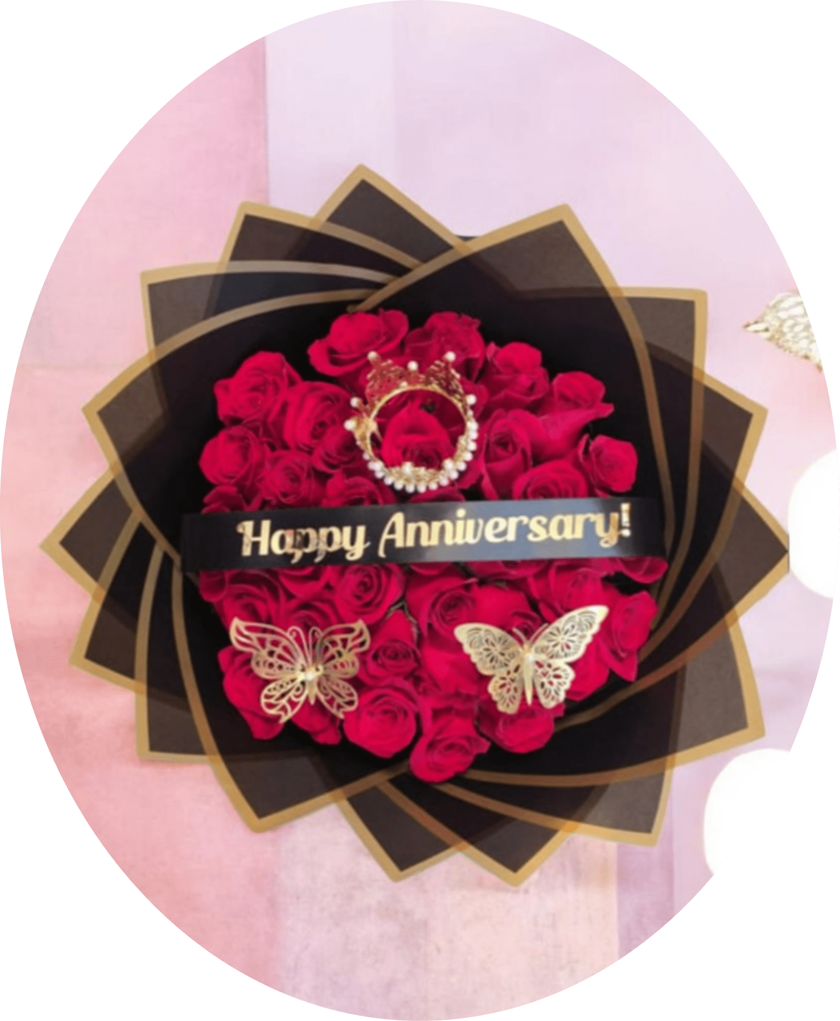 Happy Anniversary RED ROSES BOUQUETS - A dense cluster of vivid red roses wrapped in layered black paper with gold edging creates a dramatic anniversary bouquet designed to make the person you're celebrating feel deeply cherished. This anniversary roses arrangement pairs classic red blooms with bold black and gold accents-the black ribbon across the center reads "Happy Anniversary!" in gold lettering-so it reads immediately as a romantic, celebratory gift for a spouse, partner, or longtime love.  The bouquet is finished with decorative black-and-gold wrap and delicate butterfly decorations that add a touch of whimsy and movement against the rich red petals. The strong red-and-black contrast gives a luxe, statement look that suits milestone anniversaries or any moment when you want the recipient to feel seen and adored. Order this arrangement to convey passion and elegance; it arrives ready to display and delights with its precise, high-impact styling.