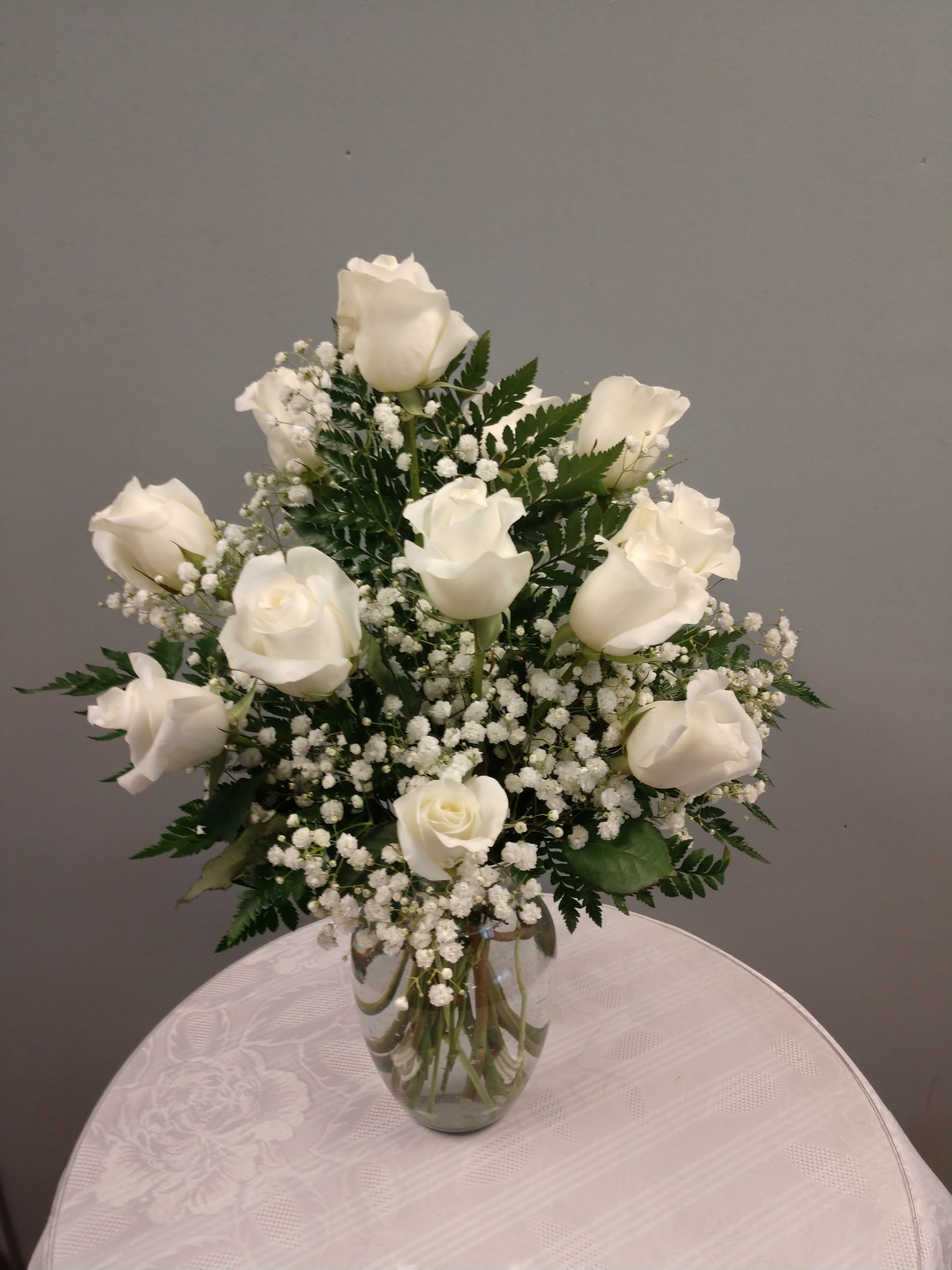 White roses arranged in a clear glass vase with baby's breath