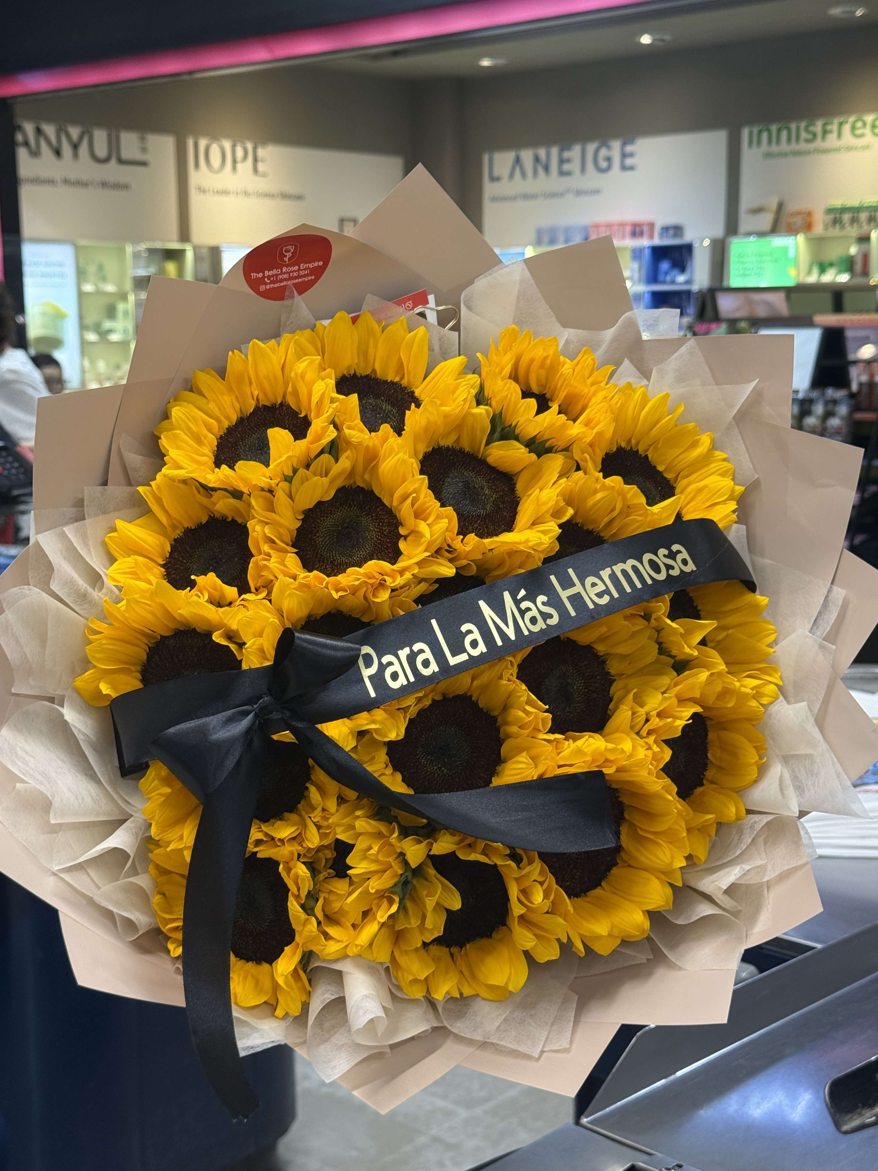 Bouquet of yellow sunflowers wrapped in beige paper with a black ribbon