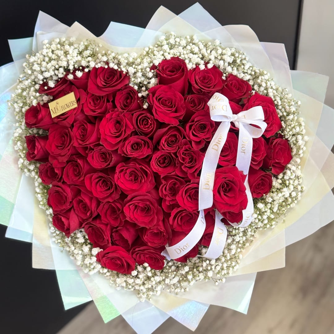 Heart-shaped bouquet of red roses with white baby's breath and a ribbon