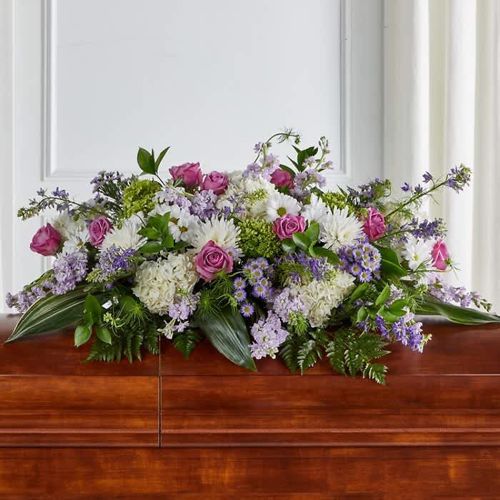Tender Embrace Casket Spray - When we lose someone dear to us, we want to respond with a fitting gesture of respect and admiration.Half casket cover arrangement of roses, hybrid lilies and monte casino, lavender cremones, spider mums and stock, purple waxflower and fresh greenery Hydrangea etc              Stock  