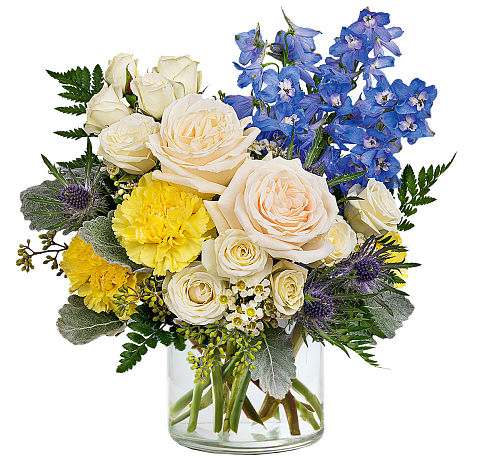 Bouquet of white roses, blue delphinium, and yellow carnations in a glass vase.