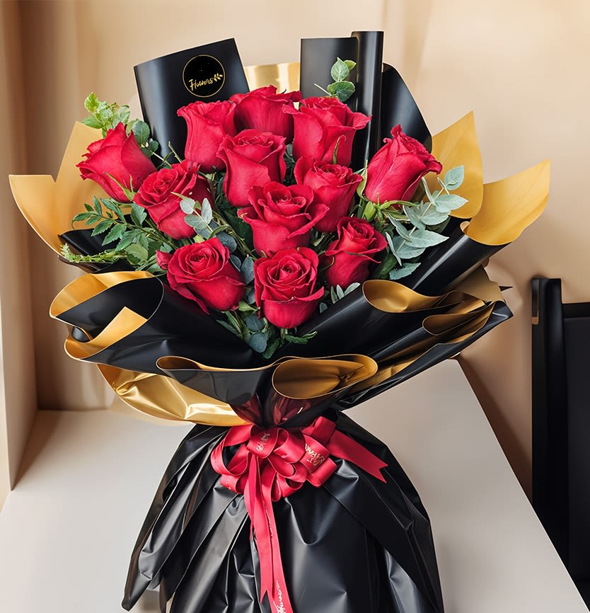 Bouquet of red roses wrapped in black and gold paper with a red ribbon