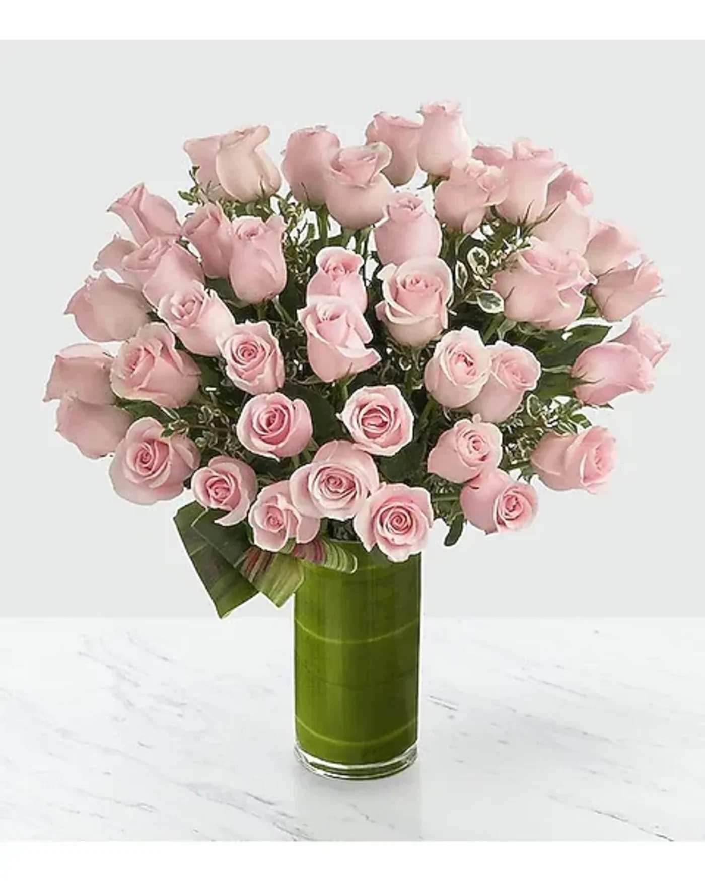 Pink roses arranged in a tall green glass vase