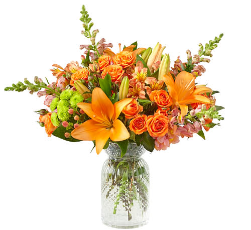 Orange lilies and roses arranged in a clear glass vase