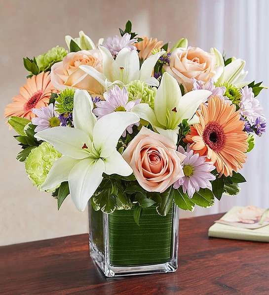 Healing Tears Multicolor Pastel - Soothe an aching heart with a sentimental tribute in soft, delicate shades. Our sympathy arrangement of pretty pastel roses, peach daisies, and white lilies, expertly gathered in a clear glass cube lined with a Ti leaf ribbon, makes for a warm gesture of comfort and healing.