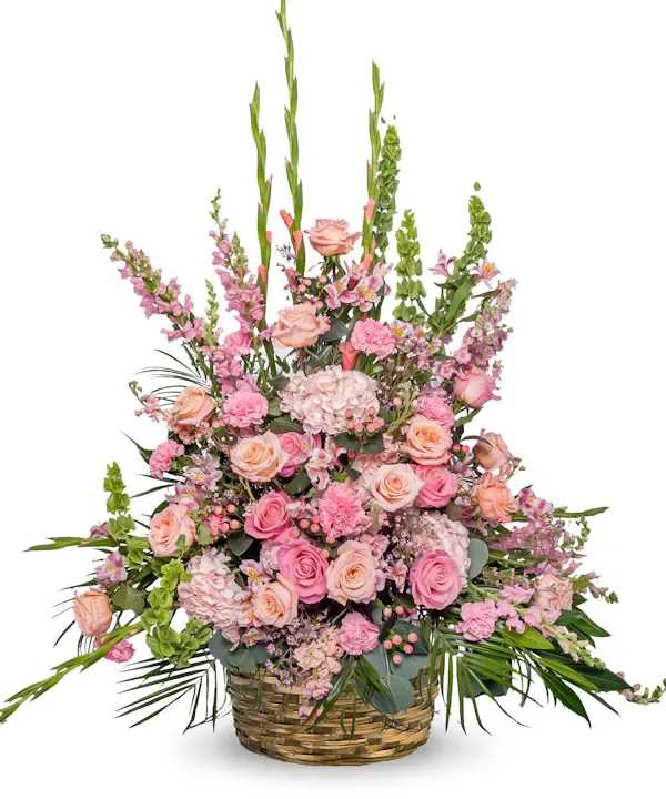 Pink and peach floral arrangement in a woven basket
