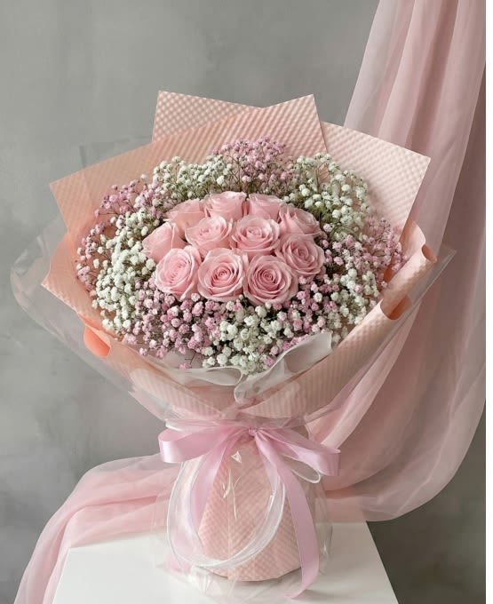 Pink rose bouquet wrapped in pastel paper with a ribbon