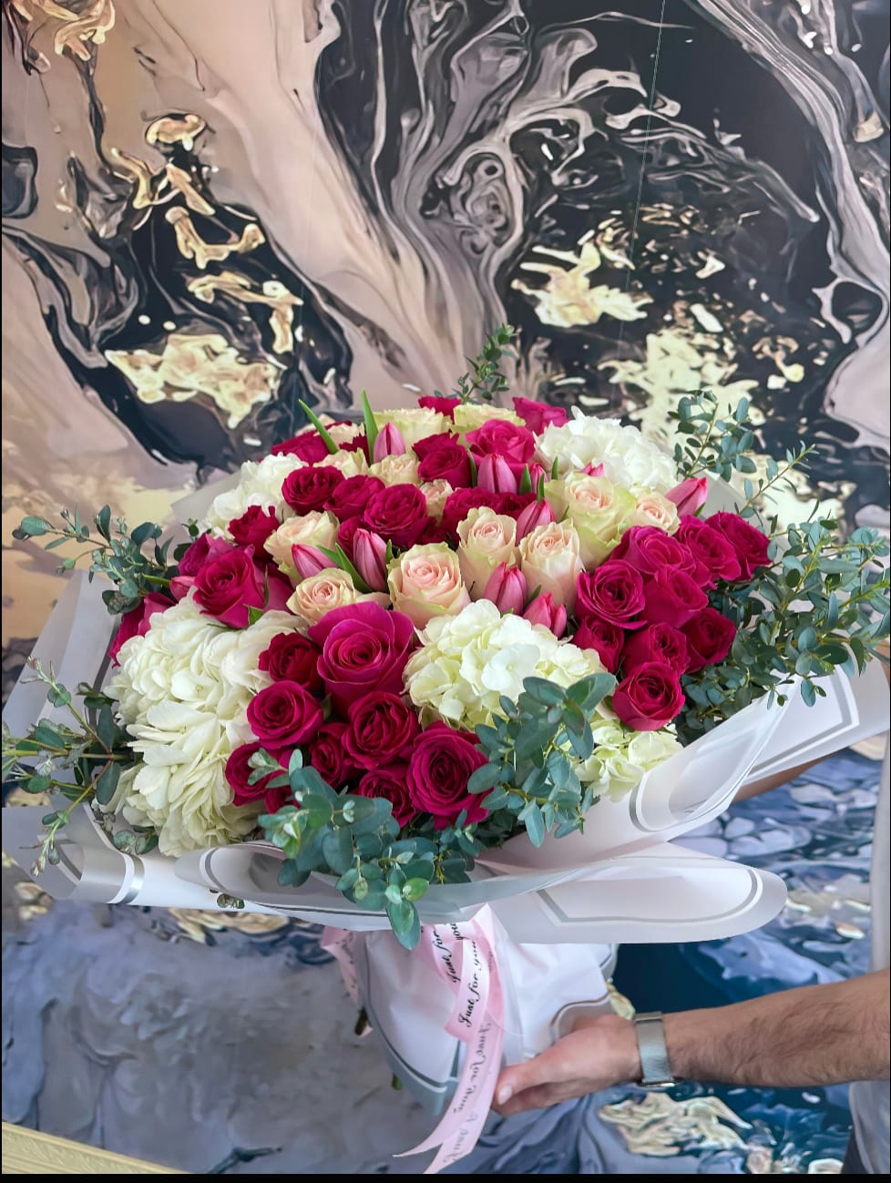 Large bouquet of pink and white roses with eucalyptus in white wrap