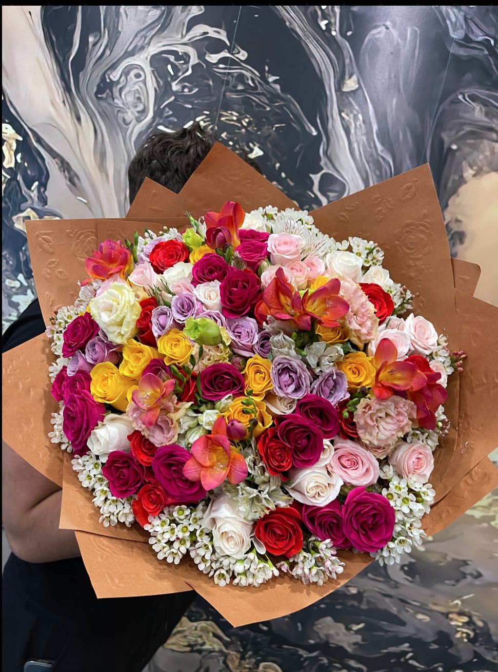 Large bouquet of multicolored roses with brown paper wrapping