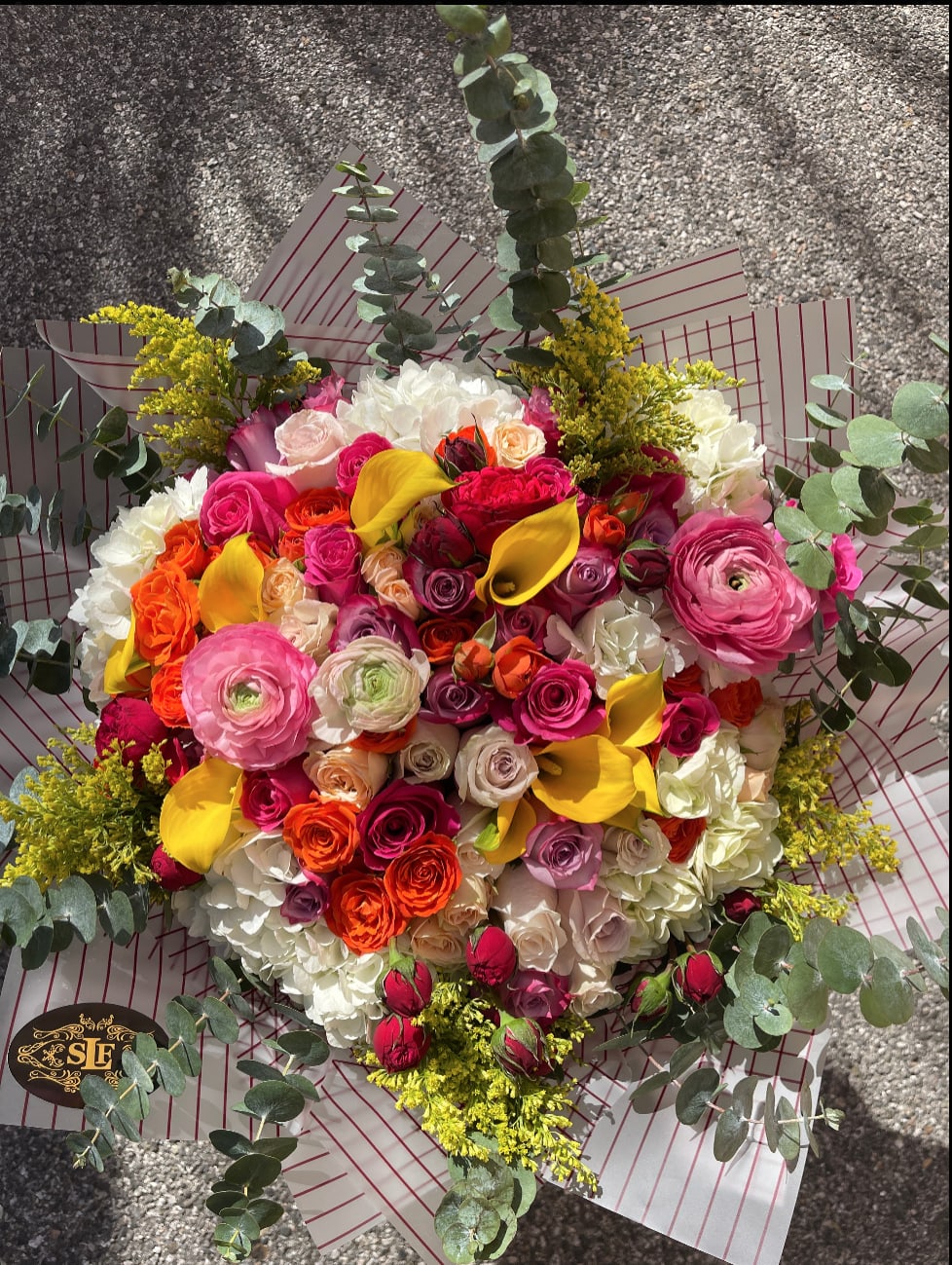 Large bouquet of pink, orange, yellow, and white flowers with eucalyptus