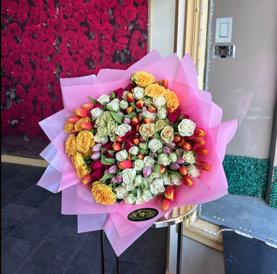 Large bouquet of roses and tulips wrapped in pink paper