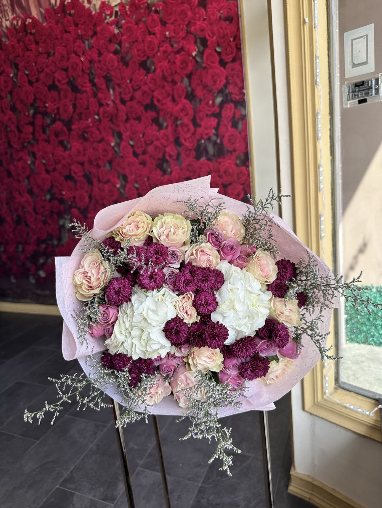 Bouquet of pink and white roses with magenta carnations in pale pink wrap