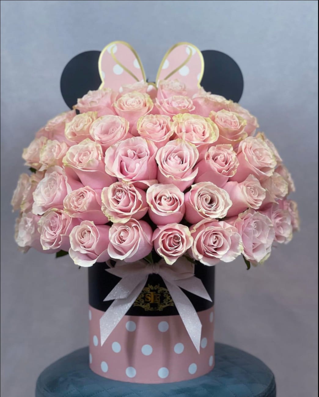Pink roses arranged in a polka-dot hat box with a ribbon and bunny ears