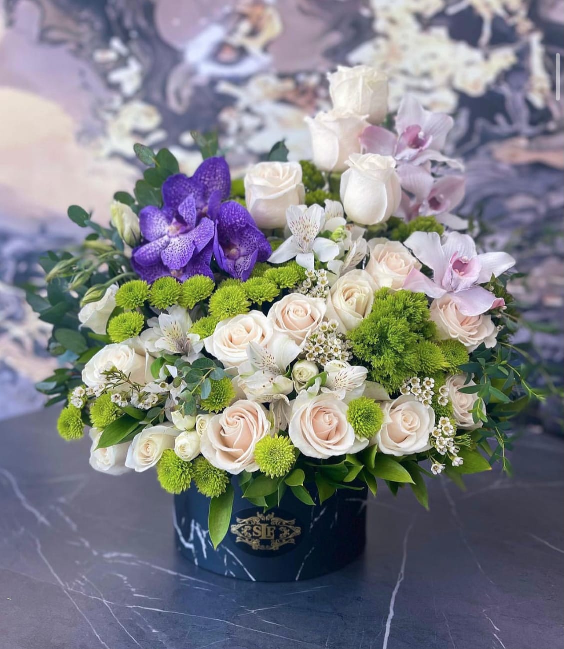 Bouquet of white and blush roses with purple orchids in a black box