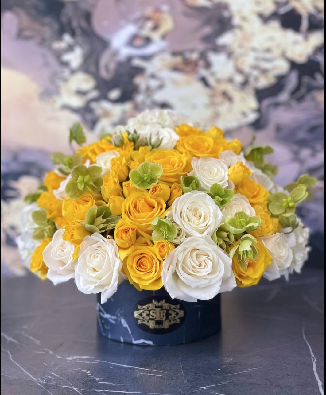 Yellow and white rose bouquet in a dark round box