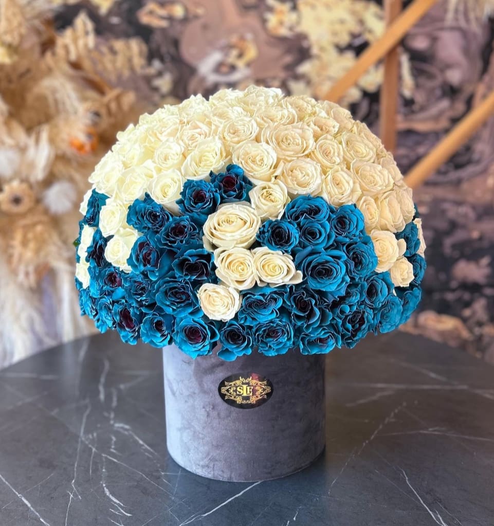 Round bouquet of cream and blue roses in a gray hat box