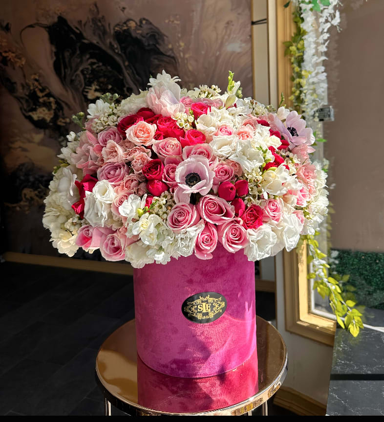 Pink and white rose arrangement in a velvet hat box