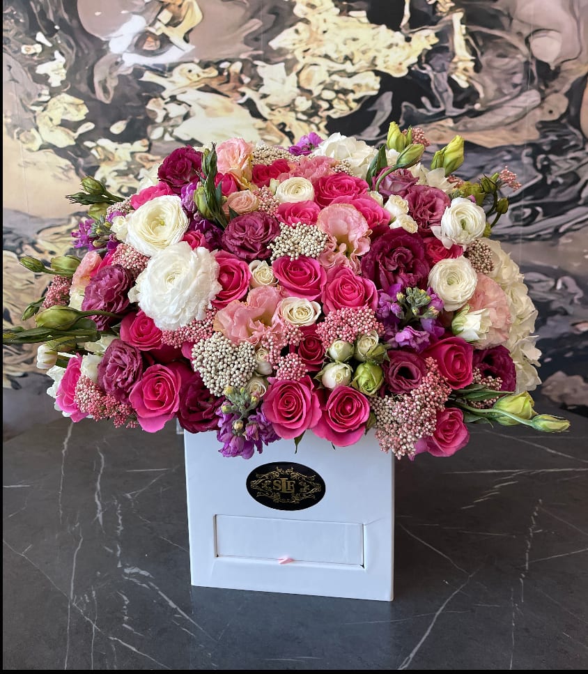 Pink, white, and purple roses arranged in a white box