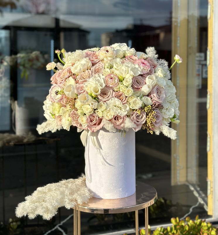 Large pastel bouquet of roses and white blooms in a white hatbox
